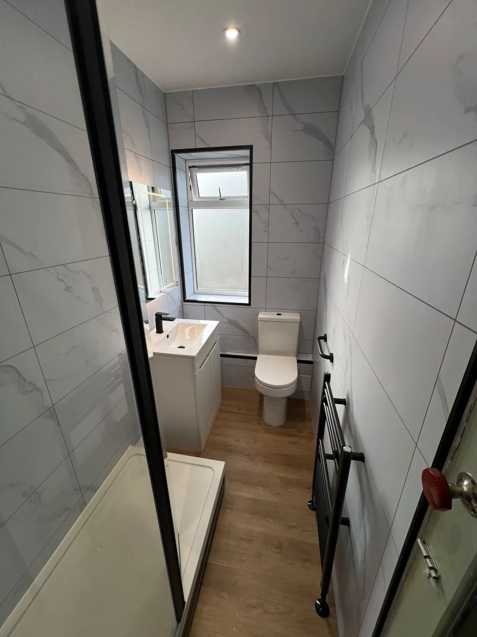 Narrow shower room with black fittings and wood-effect floor