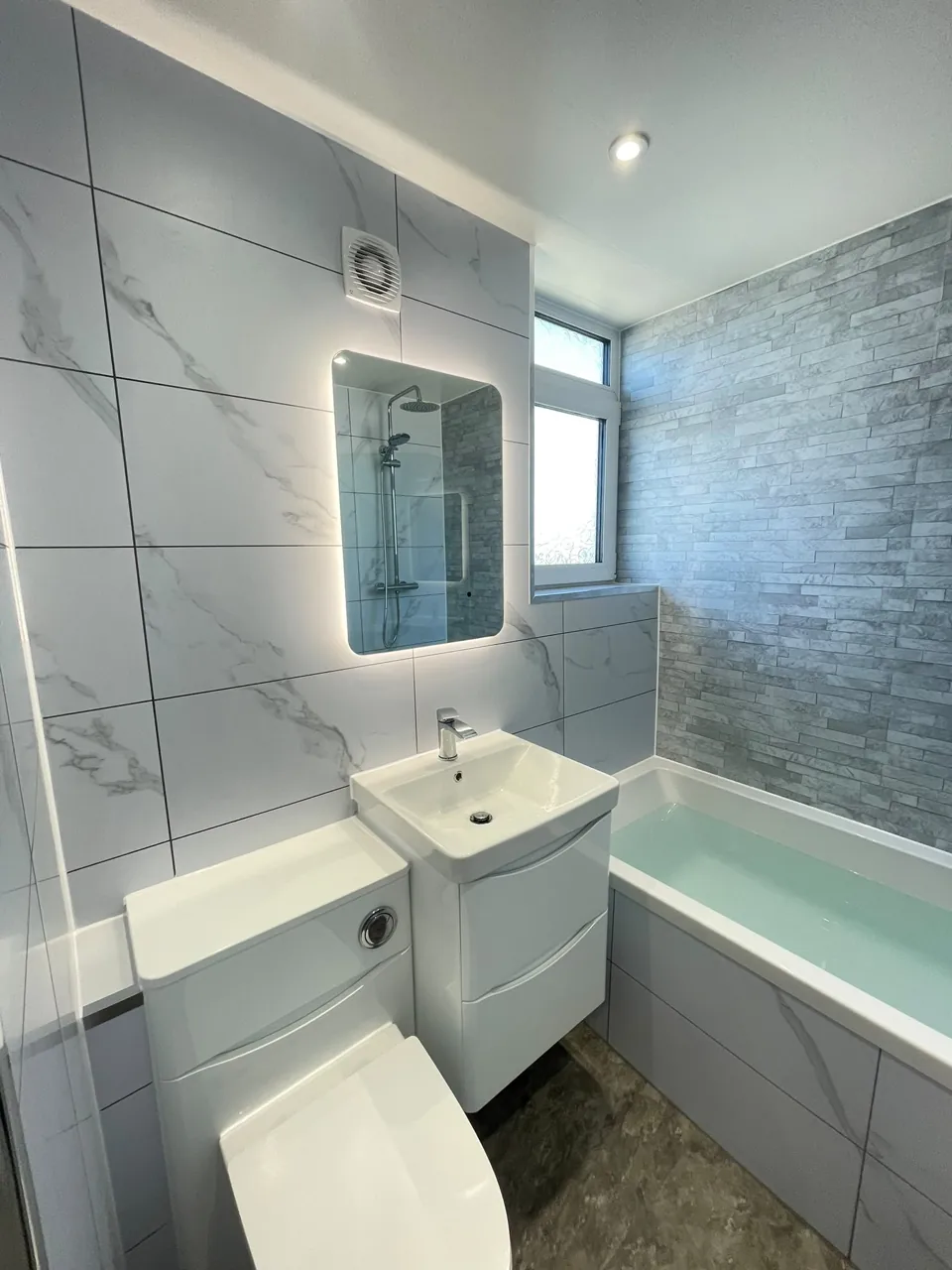 White fitted bath and vanity with marble-effect walls